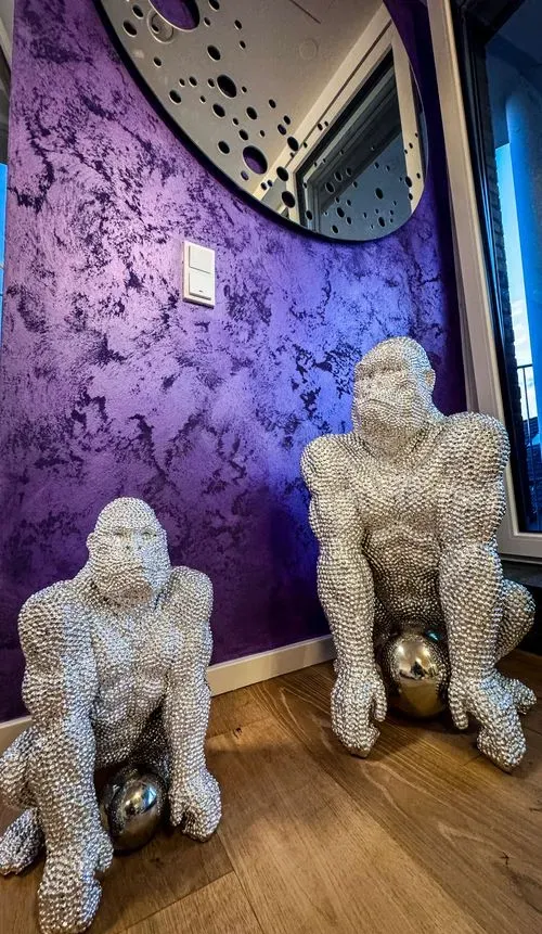 Two silver gorilla statues sitting on the floor.