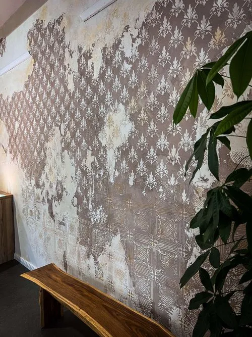 A wooden bench in front of a wall with a design of a tree.