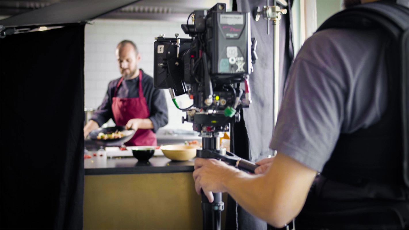 Recruitingfilm der Filmproduktion Panda Pictures aus München und Ulm für Reviderm. Ein Kameramann filmt in einer Szene einen Darsteller in einer Küche.