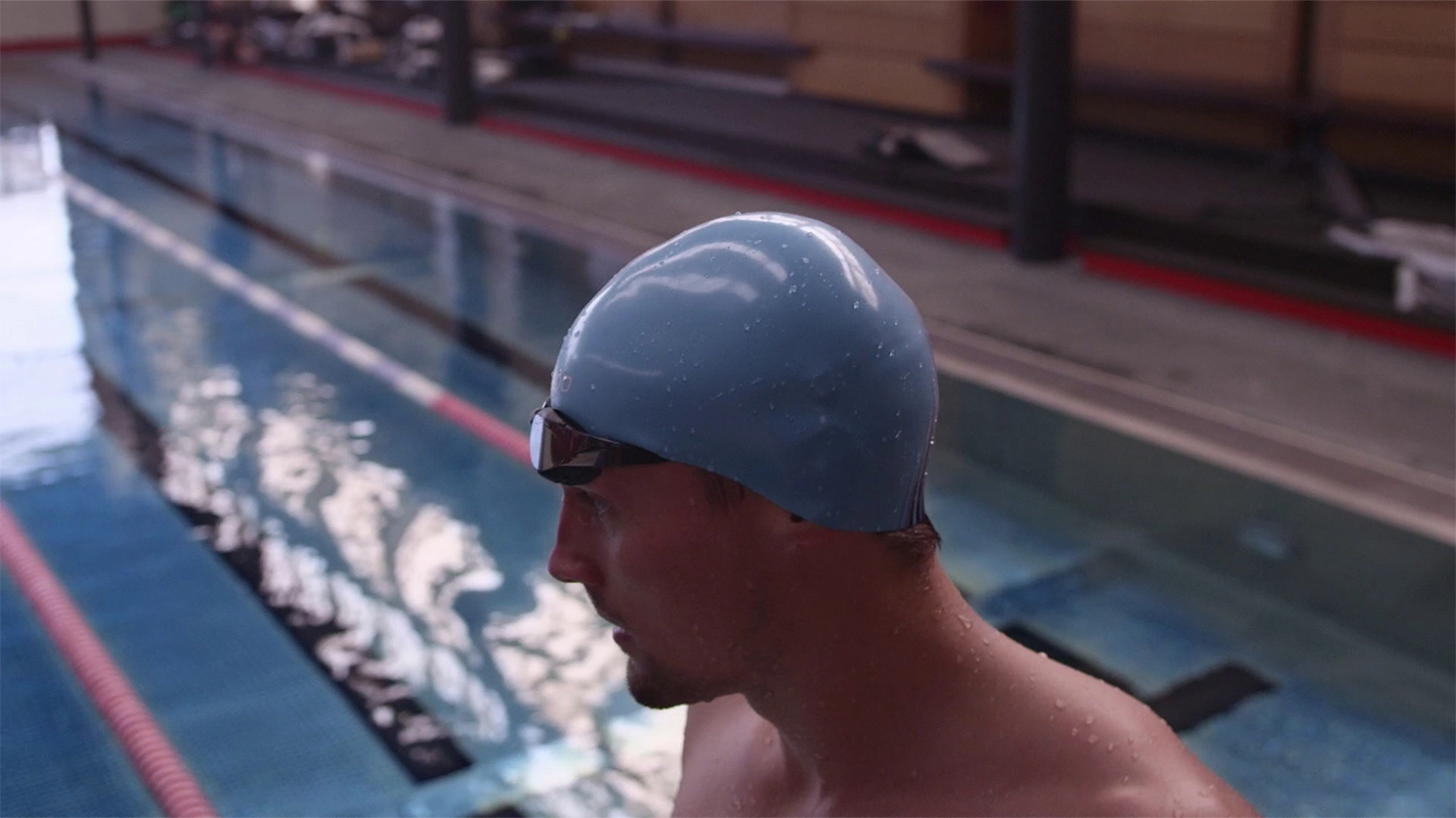 Imagefilm der Filmproduktion Panda Pictures aus München und Ulm für Speedo. Nahaufnahme eines Schwimmers mit Kappe und Brille am Beckenrand, fokussiert und bereit für die Aufnahme.