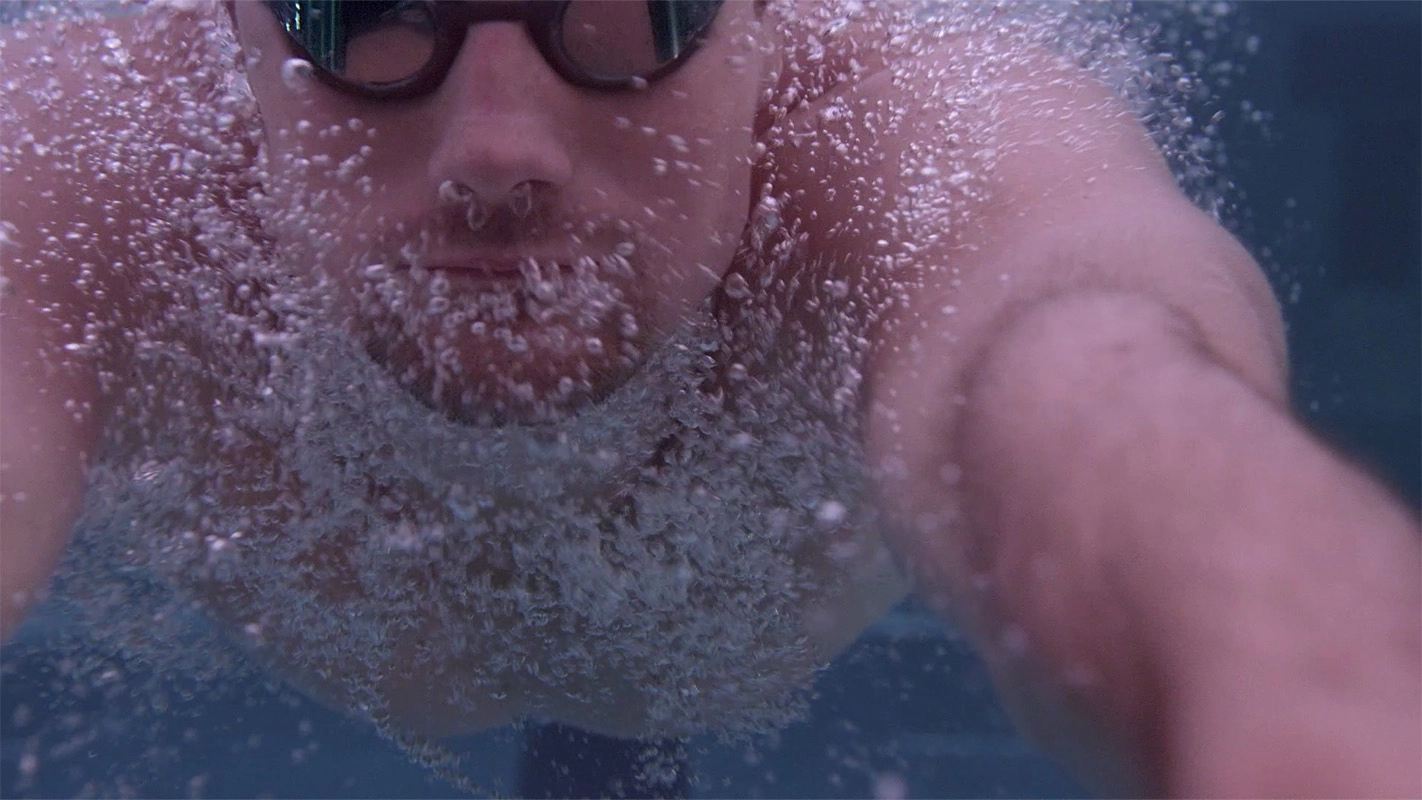 Imagefilm der Filmproduktion Panda Pictures aus München und Ulm für Speedo. Nahaufnahme des Gesichts eines Schwimmers unter Wasser mit vielen Blasen. Die Szene ist mit filmischen Lichteffekten inszeniert.