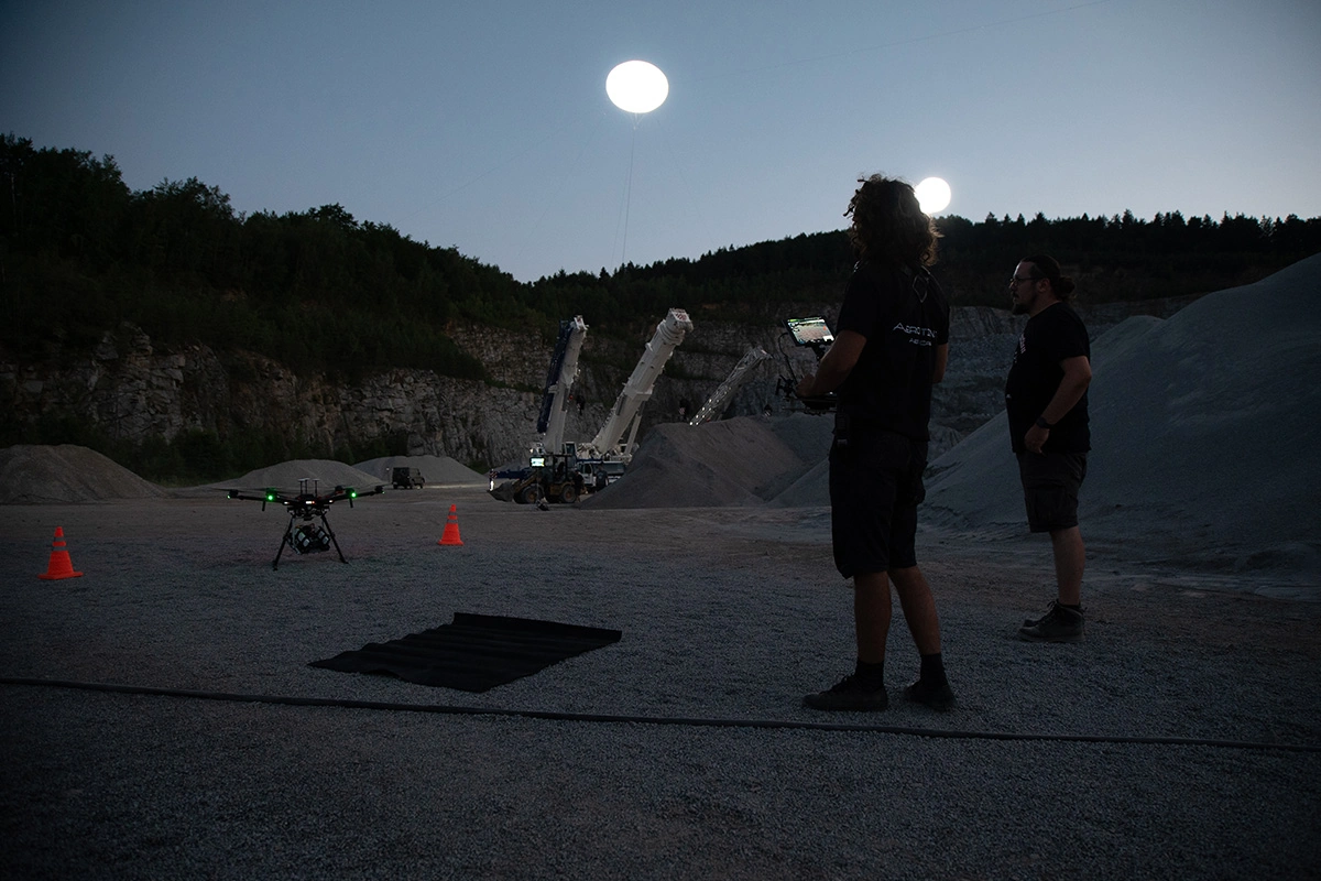Imagefilm der Filmproduktion Panda Pictures aus München und Ulm für Maxikraft. Zwei Beleuchter oder Oberbeleuchter am Filmset steuern Drohnen, die künstliche Lichtquellen für eine nächtliche Aufnahme tragen.
