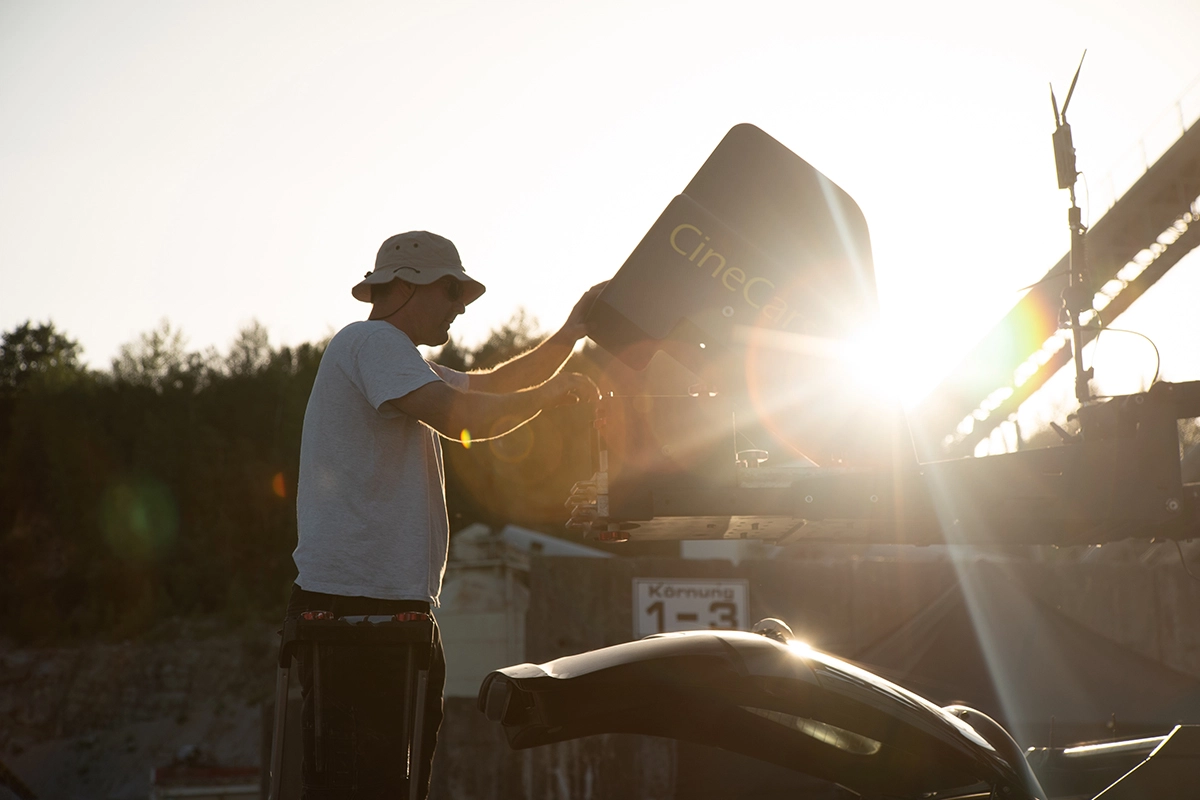 Imagefilm der Filmproduktion Panda Pictures aus München und Ulm für Maxikraft. Ein Kamera-Assistent oder Grip montiert Kamera-Equipment auf dem CineCar, einem speziell angepassten Fahrzeug für Filmaufnahmen während der Fahrt.
