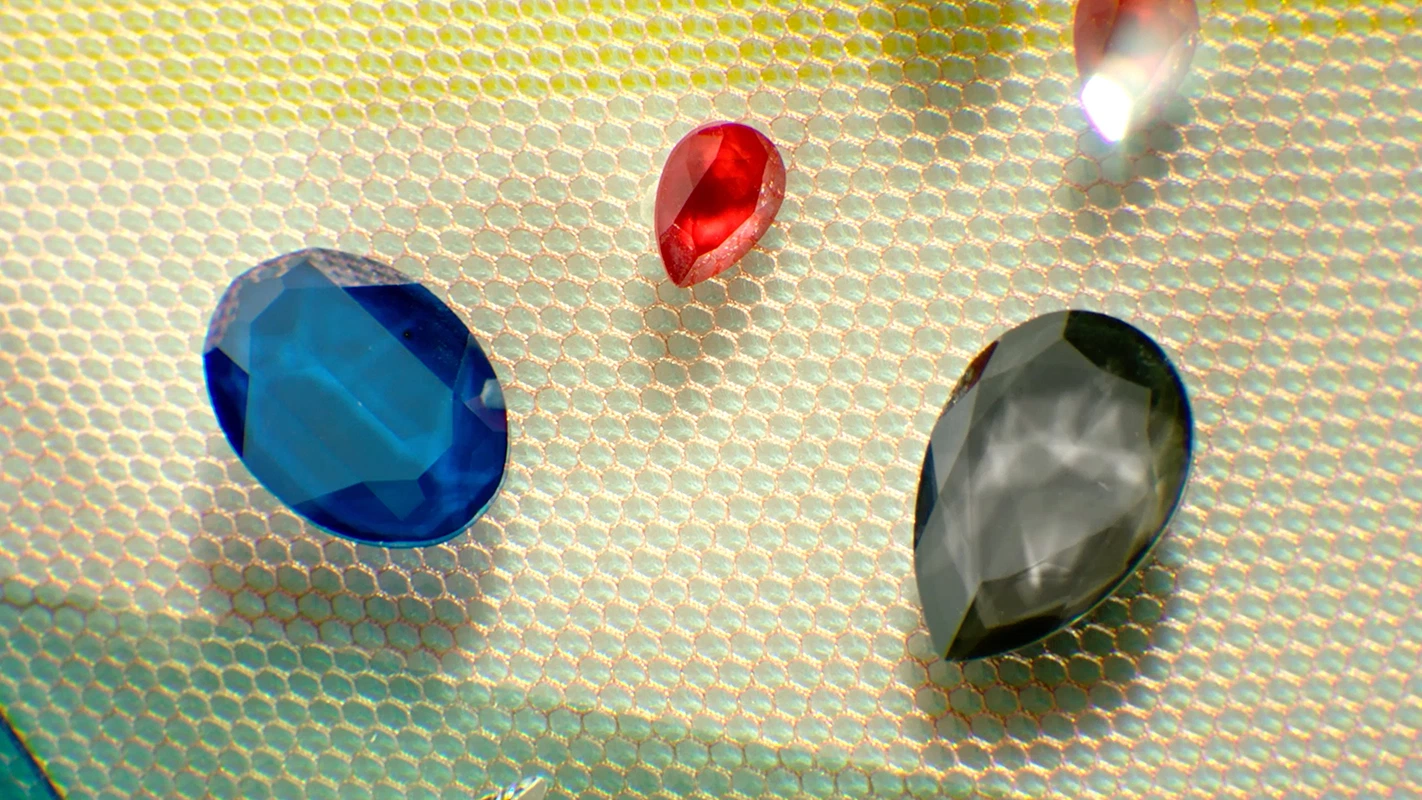 Filmproduktion Panda Pictures aus München und Ulm. Imagefilm von Swarovski. Drei bunte Kristalle (blau, rot, grau) liegen auf einem feinen Netzgewebe, ein detailliertes Set-Design für Produktaufnahmen.