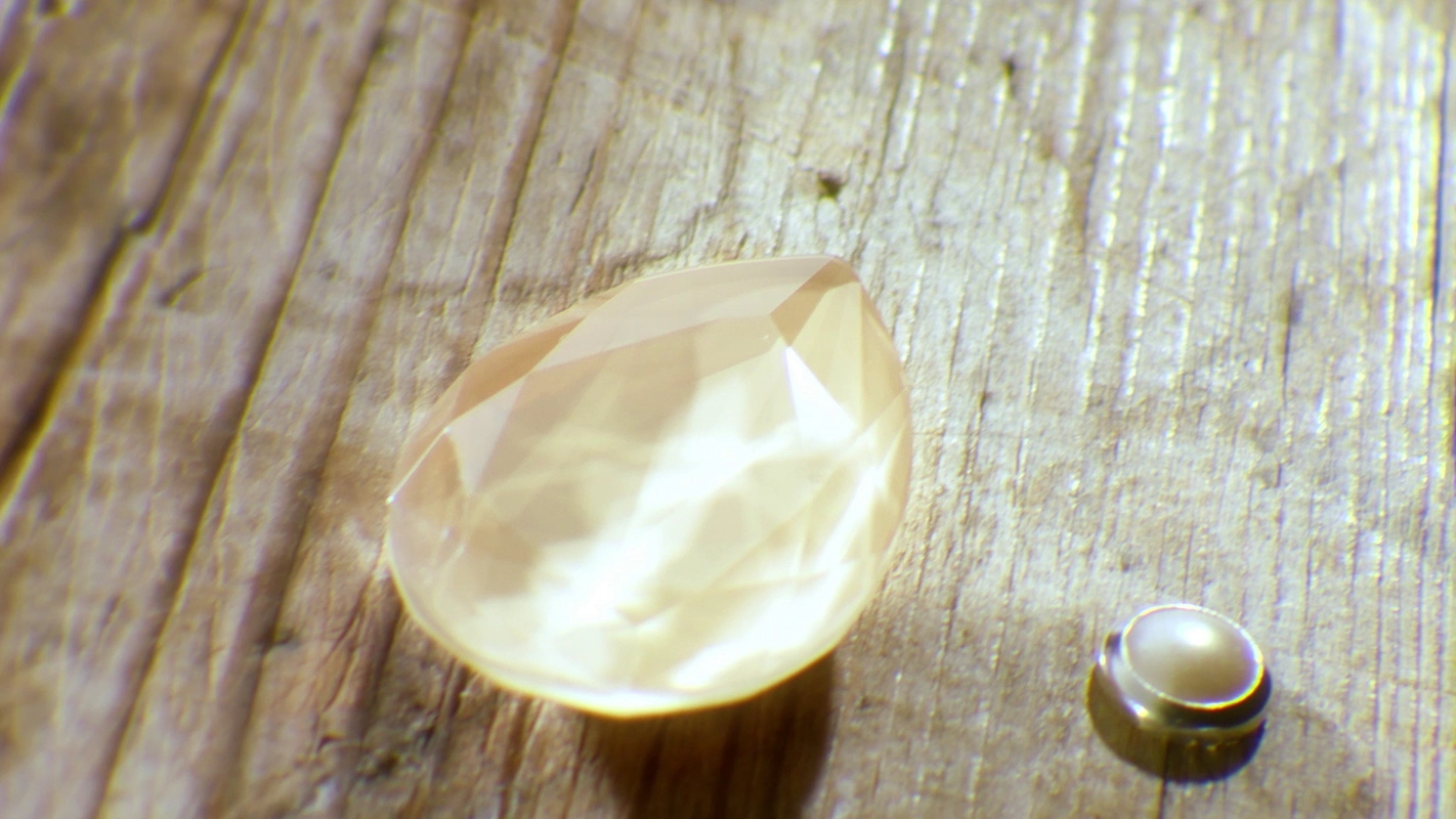 Filmproduktion Panda Pictures aus München und Ulm. Imagefilm von Swarovski. Ein hellgelber Tropfen-Kristall und eine kleine Perle liegen auf rustikalem Holz, eine Makroaufnahme mit Fokus auf Materialkontrast.