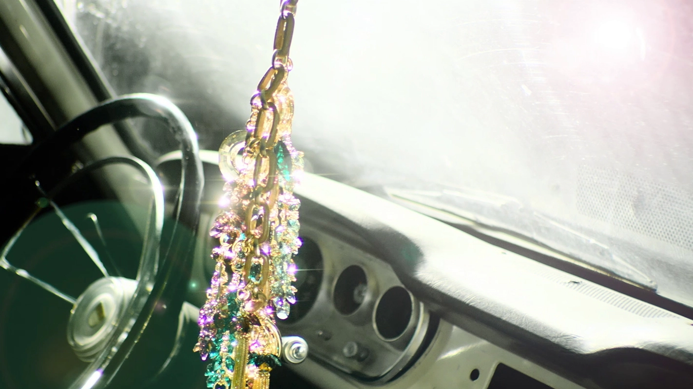 Filmproduktion Panda Pictures aus München und Ulm. Imagefilm von Swarovski. Ein glitzernder, bunter Auto-Anhänger hängt im Innenraum eines Fahrzeugs, das Lichtspiel erzeugt schöne Lens Flares.