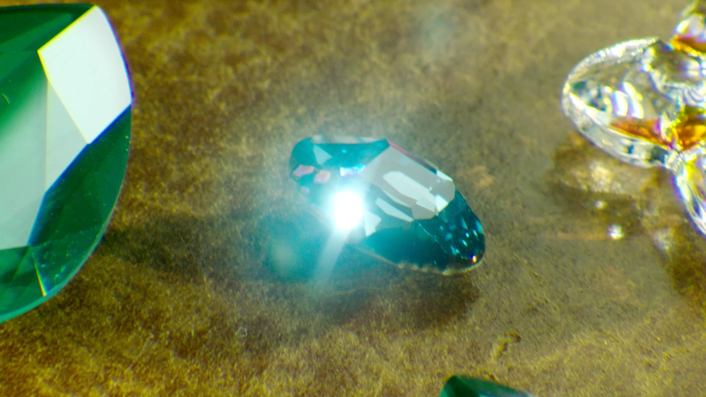 Filmproduktion Panda Pictures aus München und Ulm. Imagefilm von Swarovski. Ein glänzender blauer Kristall mit intensivem Lichtreflex auf goldenem Hintergrund, eine Nahaufnahme die den Schliff hervorhebt.