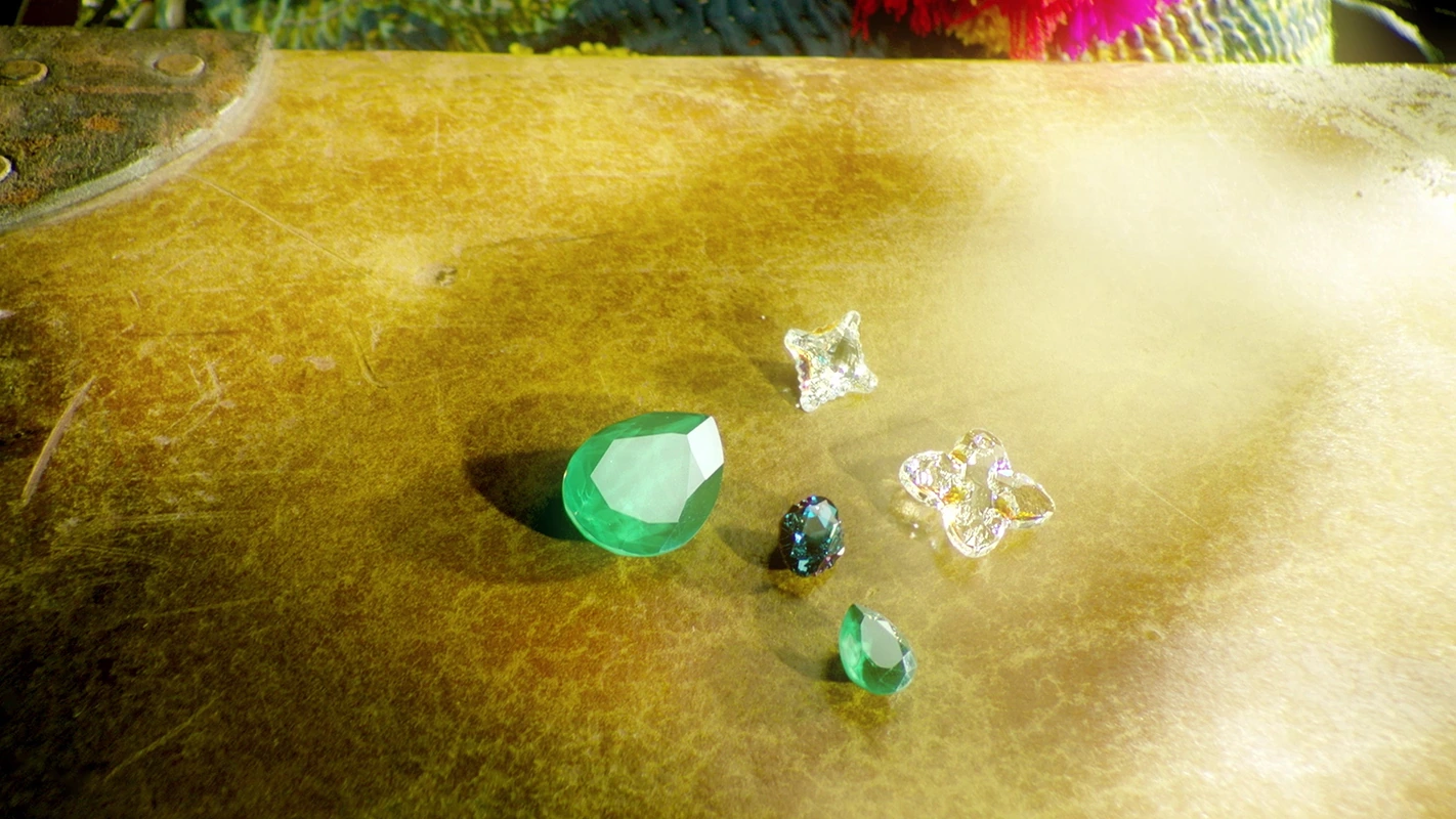 Filmproduktion Panda Pictures aus München und Ulm. Imagefilm von Swarovski. Eine Sammlung von funkelnden Edelsteinen auf einem goldenen Hintergrund, kunstvoll angeordnet für eine Luxus-Produktaufnahme.
