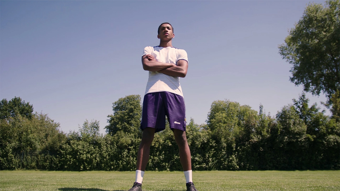 01-Produktfilm der Filmproduktion Panda Pictures aus München und Ulm für Hammer Sport. Ein junger Fußballspieler steht selbstbewusst mit verschränkten Armen auf einem grünen Rasen, eine motivierende Szene.