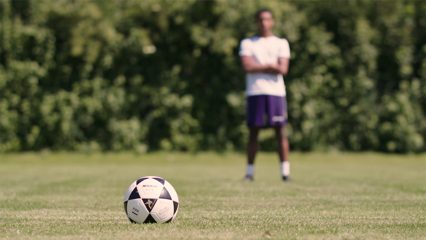 Produktfilm der Filmproduktion Panda Pictures aus München und Ulm für Hammer Sport. Ein Fußball liegt im Vordergrund auf dem Rasen, im Hintergrund steht ein Spieler unscharf, Fokus auf das Sportgerät.