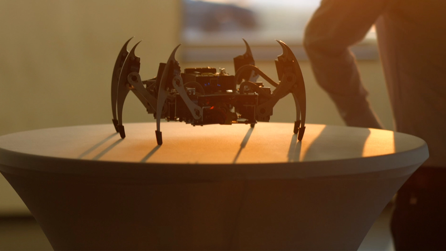 Imagefilm der Filmproduktion Panda Pictures aus München und Ulm für TechFounders. Eine detailreiche Aufnahme eines futuristischen Roboters auf einem Podest, atmosphärisch beleuchtet durch warmes Gegenlicht.
