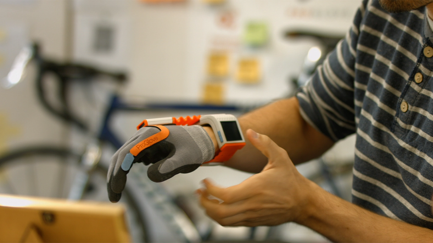 Imagefilm der Filmproduktion Panda Pictures aus München und Ulm für TechFounders. Eine Detailaufnahme zeigt einen Darsteller, der einen "ProGlove"-Handschuh mit integriertem Scanner am Handgelenk trägt und präsentiert.