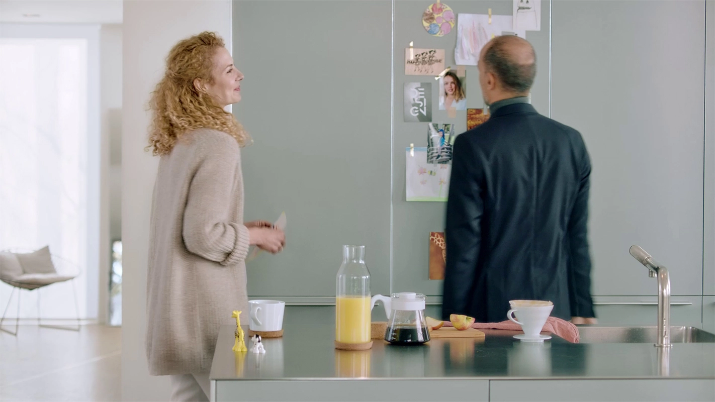 Imagefilm der Filmproduktion Panda Pictures aus München und Ulm für GIRA. Zwei Darsteller in einer modernen Küche: die Darstellerin steht am Tresen, während der Darsteller Notizen an einem Whiteboard betrachtet.