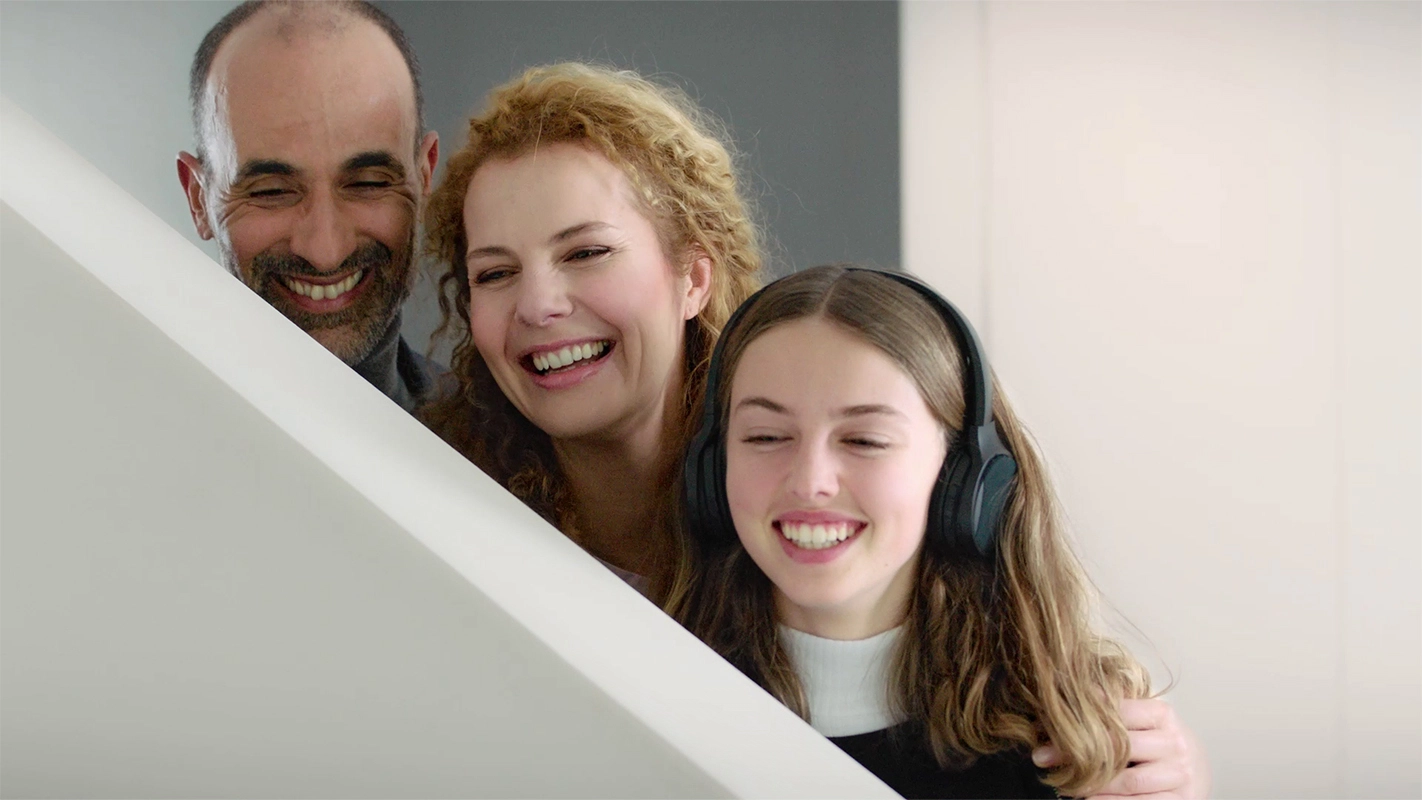 Imagefilm der Filmproduktion Panda Pictures aus München und Ulm für GIRA. Eine Familie lacht gemeinsam mit der Tochter, die Kopfhörer trägt, was eine fröhliche Momentaufnahme der Filmproduktion darstellt.
