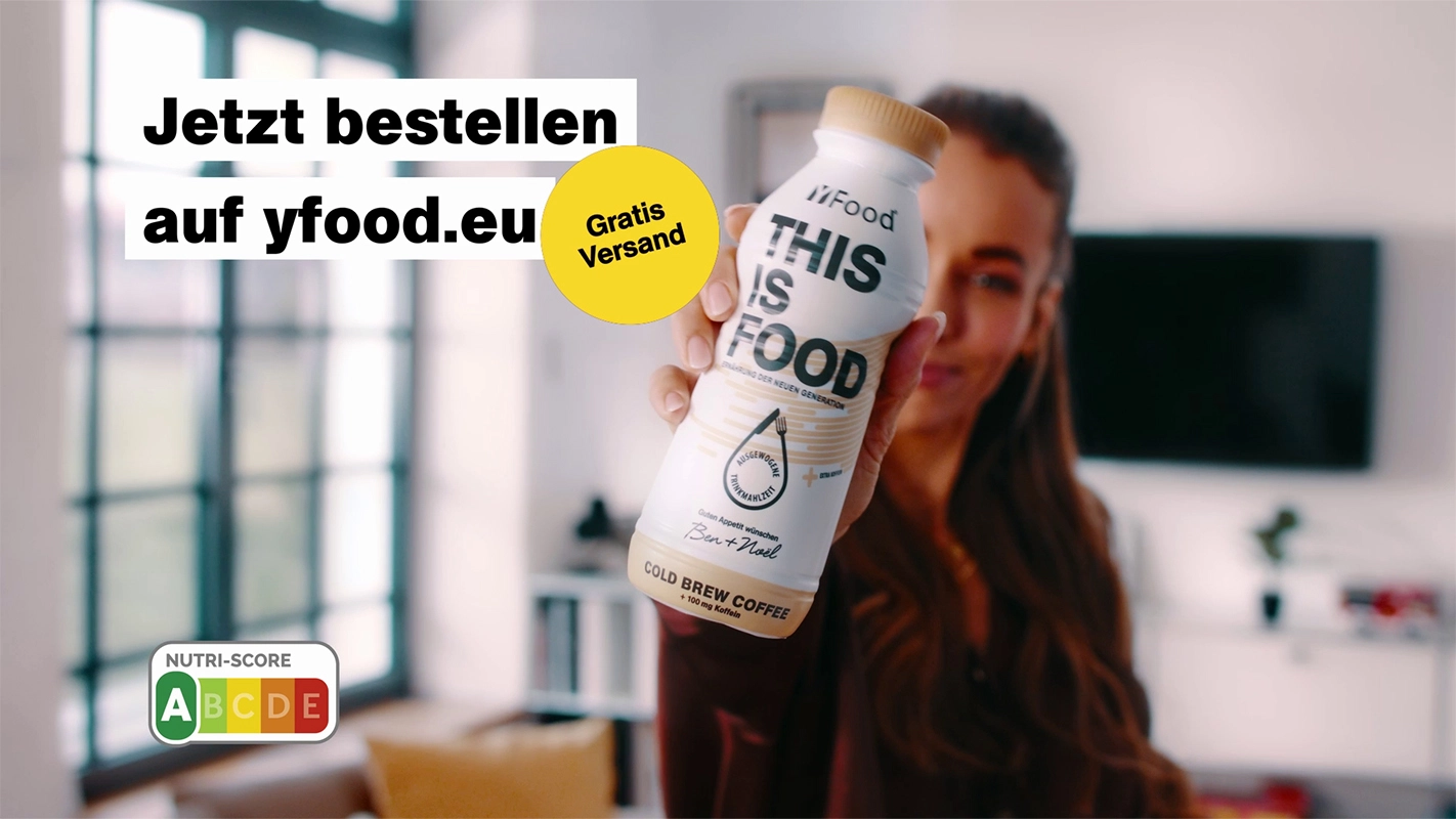 TV Werbefilm der Filmproduktion Panda Pictures aus München und Ulm für yFood. Eine unscharfe Darstellerin präsentiert eine yFood-Flasche mit klarem Fokus auf das Produkt und Bestelldetails.