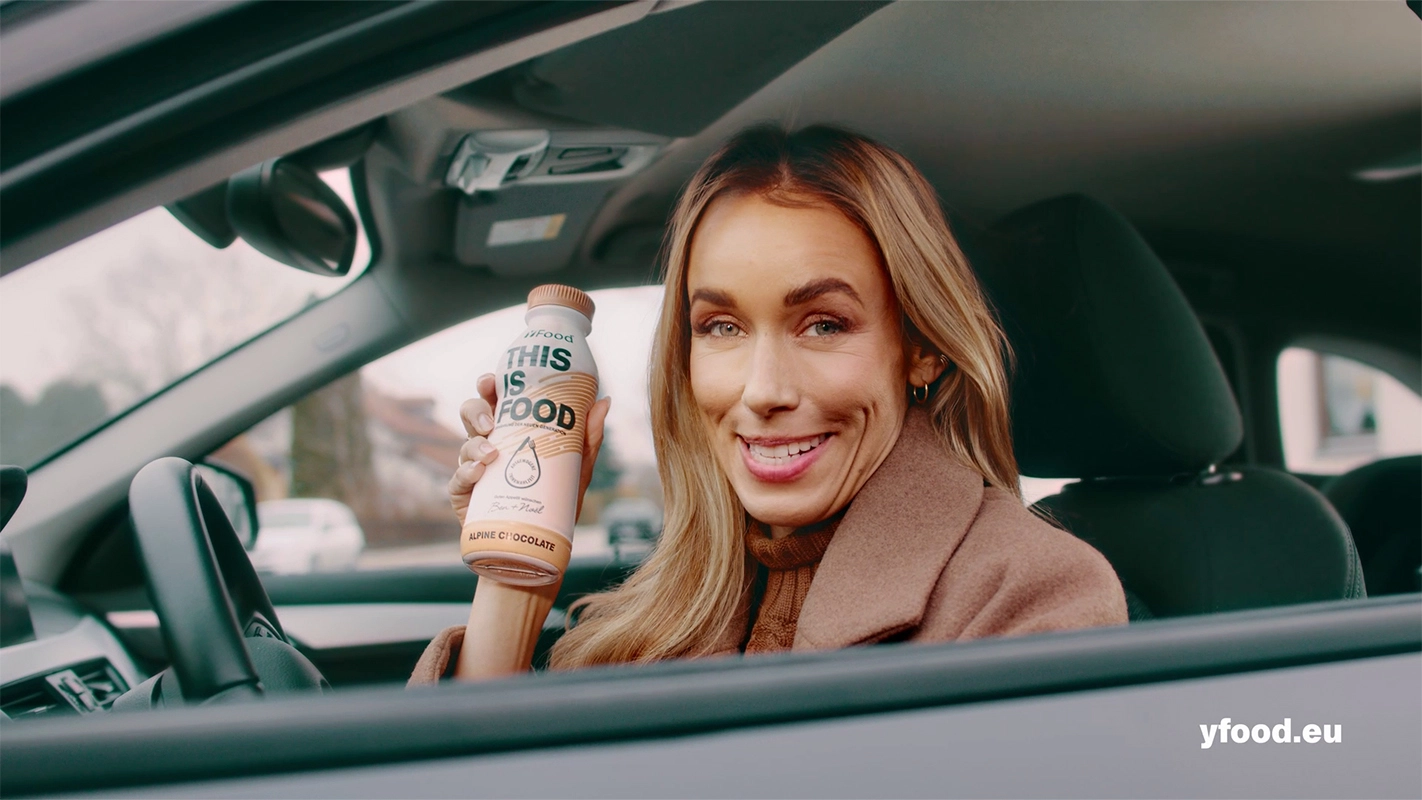TV Werbefilm der Filmproduktion Panda Pictures aus München und Ulm für yFood. Eine lächelnde Darstellerin präsentiert ein yFood-Getränk am Steuer eines Autos, eine ideale Produktplatzierung.