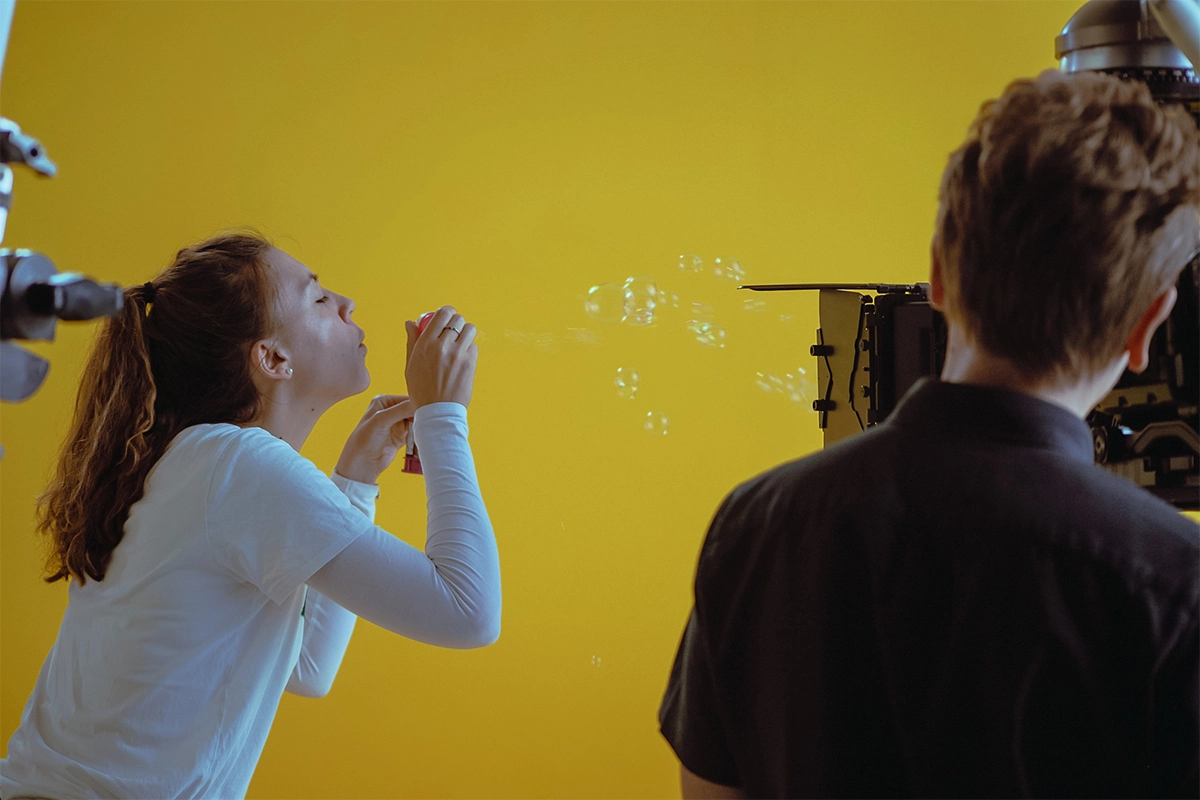 Produktfilm der Filmproduktion Panda Pictures aus München und Ulm für Juzo. Eine Darstellerin bläst Seifenblasen, eine spielerische Szene vor dem gelben Greenscreen.