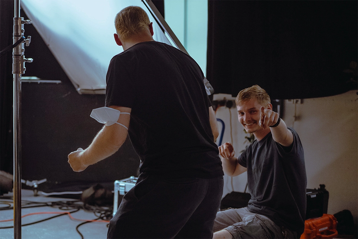 Produktfilm der Filmproduktion Panda Pictures aus München und Ulm für Juzo. Zwei Crewmitglieder interagieren am Set, einer zeigt in die Kamera, während der andere einen Scheinwerfer trägt.