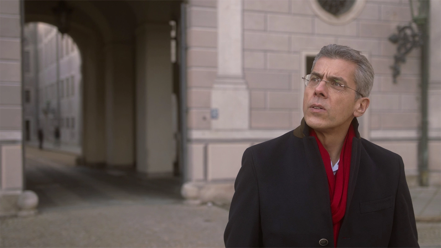 Weihnachtsfilm der Filmproduktion Panda Pictures aus München und Ulm für UniCredit. Der Protagonist mit Brille und rotem Schal blickt nachdenklich in einem Torbogen, eine szenische Aufnahme für den Weihnachtsfilm.