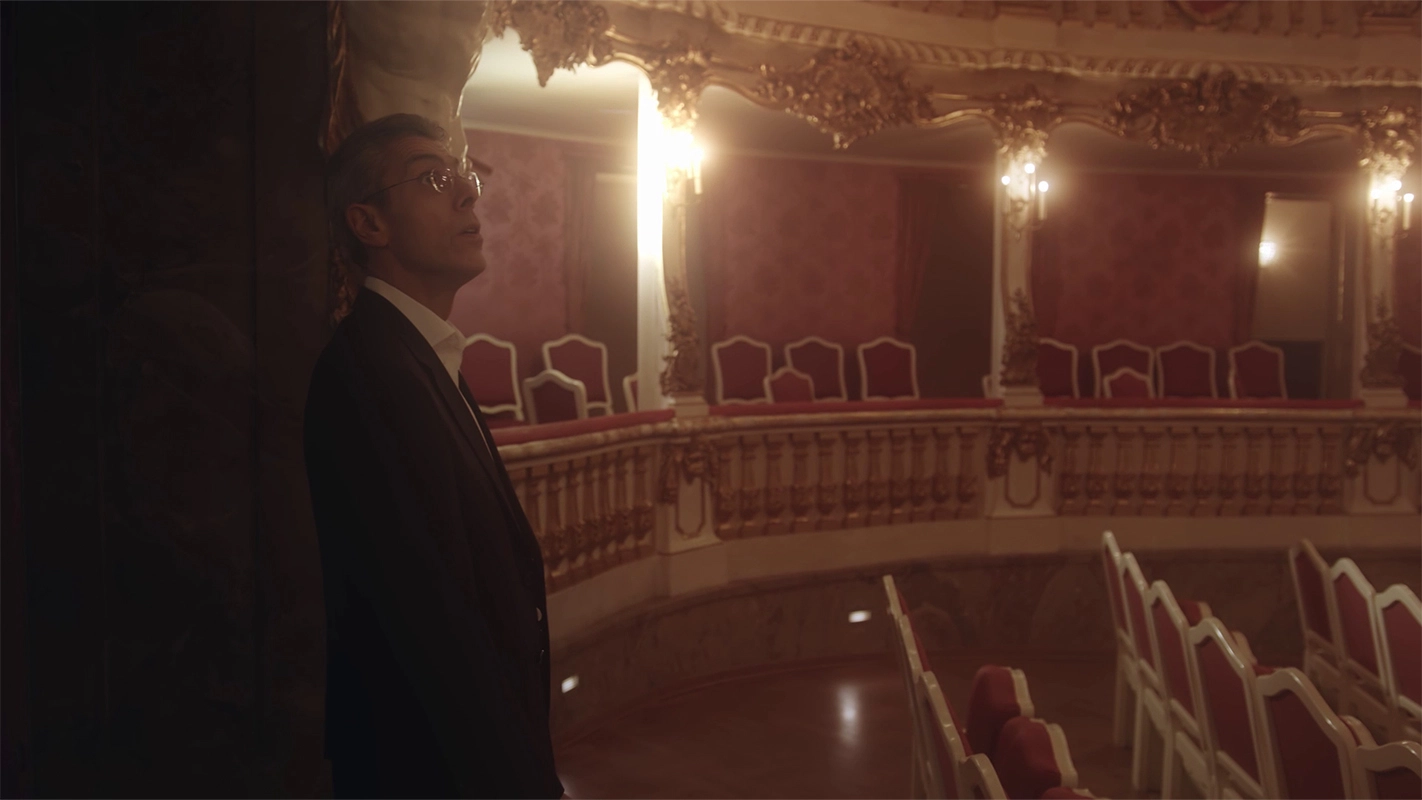 Weihnachtsfilm der Filmproduktion Panda Pictures aus München und Ulm für UniCredit. Der Protagonist steht in einem prunkvollen Theater mit roten Sitzen, eine Weitwinkelaufnahme, die die Exklusivität der Location hervorhebt.