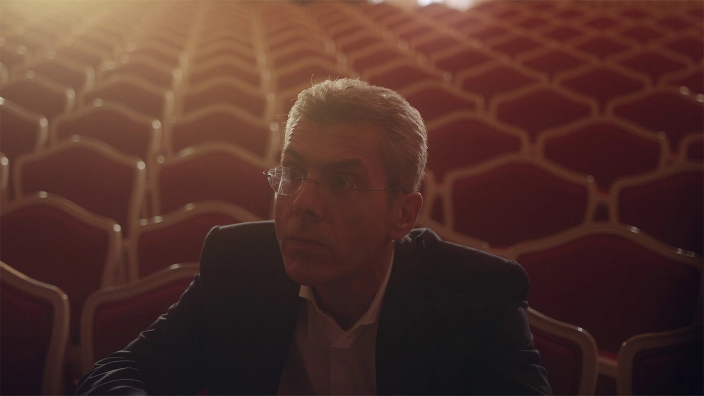 Weihnachtsfilm der Filmproduktion Panda Pictures aus München und Ulm für UniCredit. Nahaufnahme des Protagonisten, der in einem eleganten Theater sitzt, Licht fällt von oben und erzeugt eine besinnliche Stimmung.