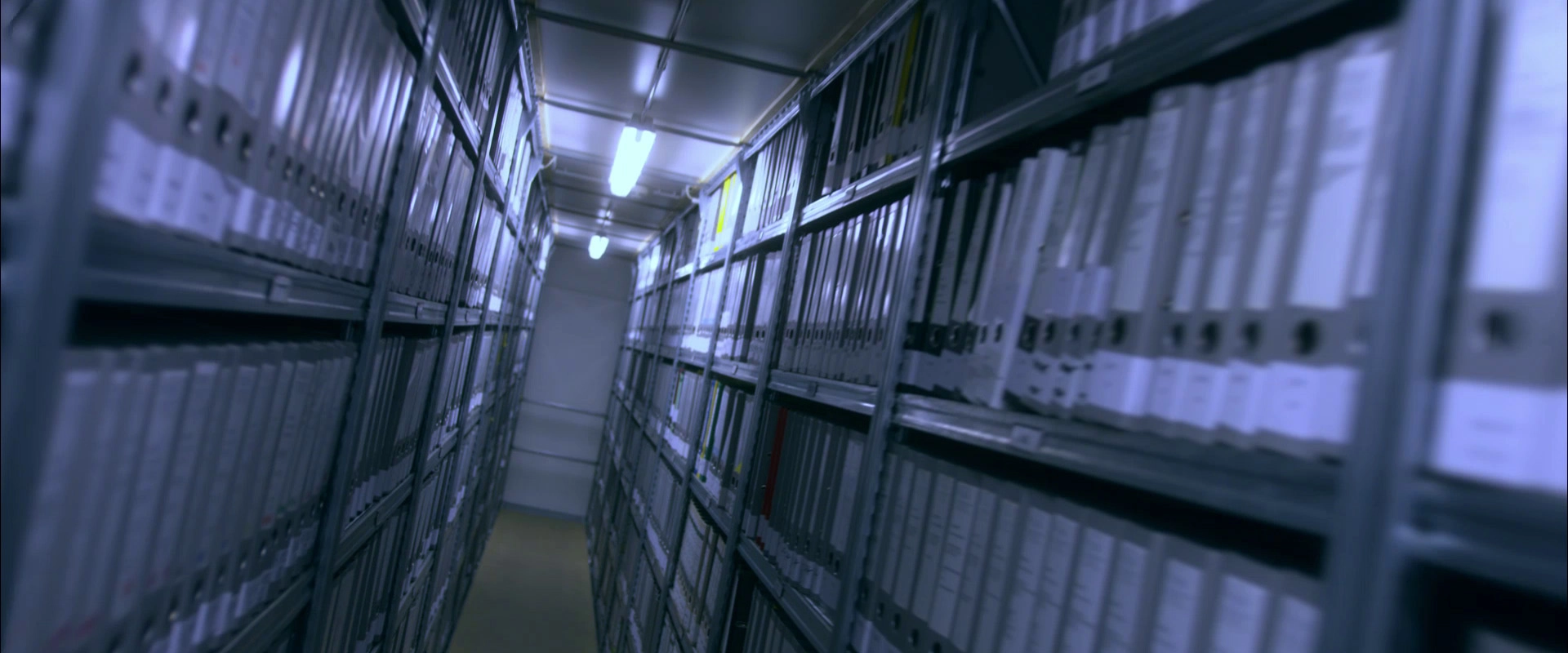 Imagefilm der Filmproduktion Panda Pictures aus München und Ulm für HARDER. Ein langer Gang in einem Archiv, gesäumt von Aktenregalen mit vielen Ordnern. Die Perspektive betont die Tiefe des Raumes.