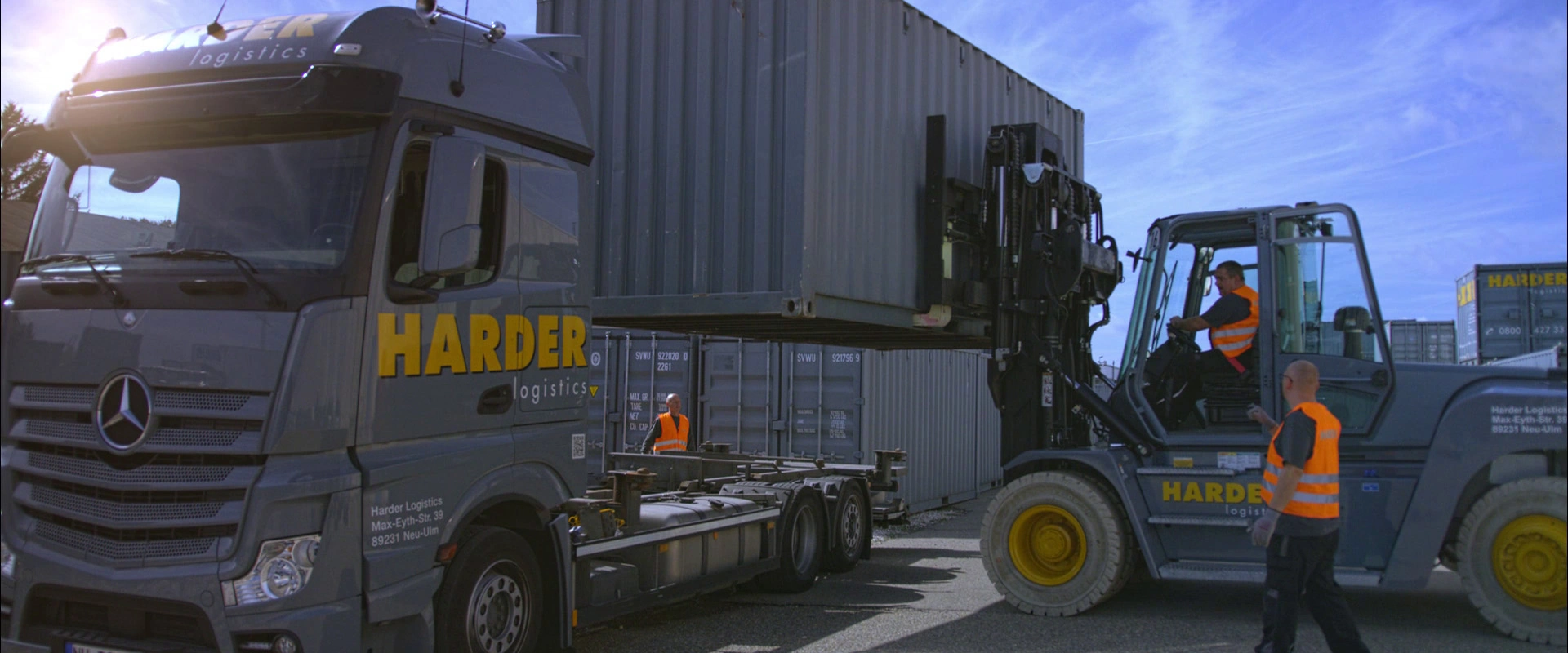 Imagefilm der Filmproduktion Panda Pictures aus München und Ulm für HARDER. Ein Gabelstapler verlädt einen Container auf einen LKW, zwei Arbeiter sind im Bild. Eine Szene, die präzise Logistik abbildet.