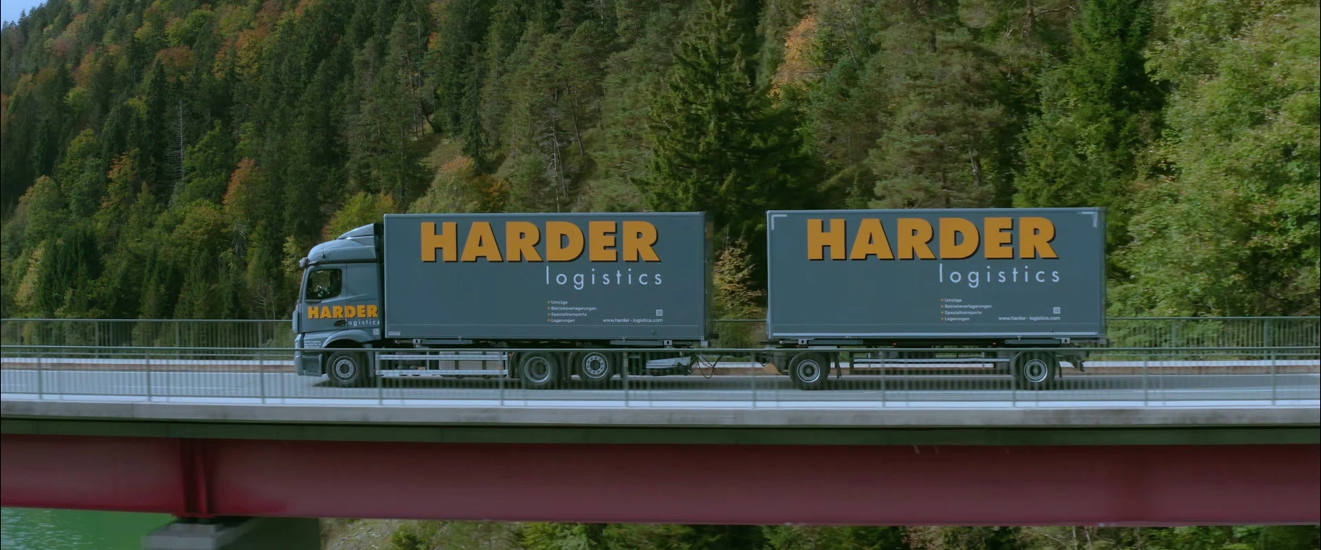 Imagefilm der Filmproduktion Panda Pictures aus München und Ulm für HARDER. Seitenansicht eines Harder-Lkws auf einer Brücke vor bewaldeten Bergen. Eine klassische Aufnahme für einen Imagefilm.