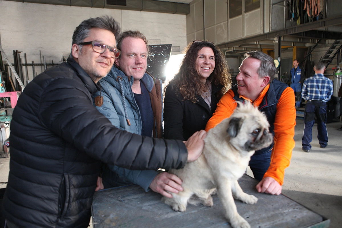 Produktfilm der Filmproduktion Panda Pictures aus München und Ulm für ifm. Produktfilm der Filmproduktion Panda Pictures aus München und Ulm für ifm. Crewmitglieder interagieren mit einem Mops am Set, eine dokumentarische Szene der Filmarbeiten.