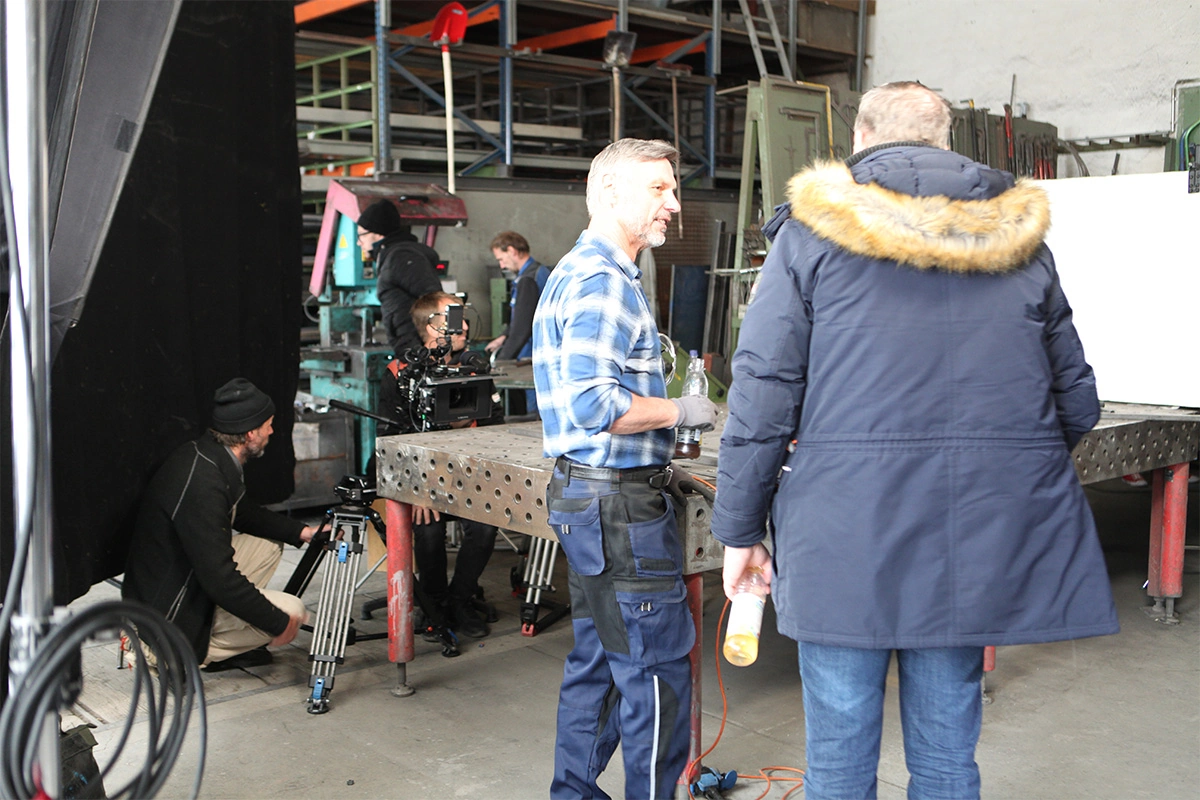 Produktfilm der Filmproduktion Panda Pictures aus München und Ulm für ifm. Produktfilm der Filmproduktion Panda Pictures aus München und Ulm für ifm. Mehrere Crewmitglieder um einen Tisch herum, im Vordergrund ein Darsteller und ein weiterer Darsteller.