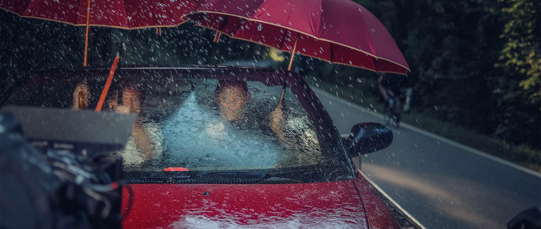 Imagefilm der Filmproduktion Panda Pictures aus München und Ulm für Scheuermann & Heilig. Eine Szene im Regen, bei der sich Darsteller mit einem roten Regenschirm in einem Cabrio vor der Kamera befinden, zeigt die filmische Inszenierung.