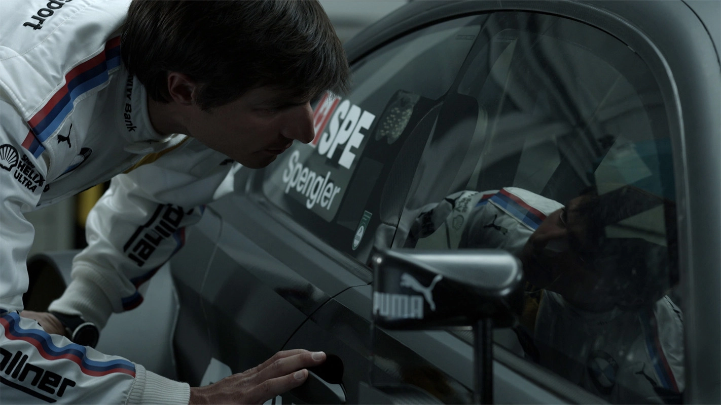 Filmproduktion Panda Pictures aus München und Ulm zum Thema Financial Services Imagefilm. Der Fahrer blickt konzentriert in das Cockpit seines Fahrzeugs. Solche Momente der Fokussierung werden bei den Dreharbeiten gezielt eingefangen.