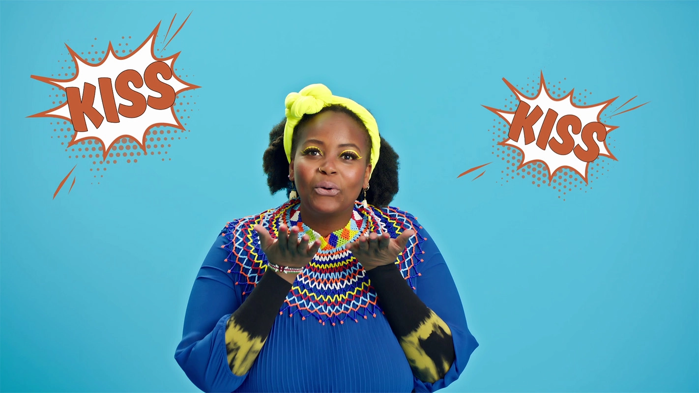 Filmproduktion Panda Pictures aus München und Ulm zum Thema JuZo – show your inner colors. Eine Frau in einem farbenfrohen Outfit wirft einen Kuss in die Kamera. Bei den Dreharbeiten für den Werbespot wird auf eine direkte und spielerische Interaktion gese