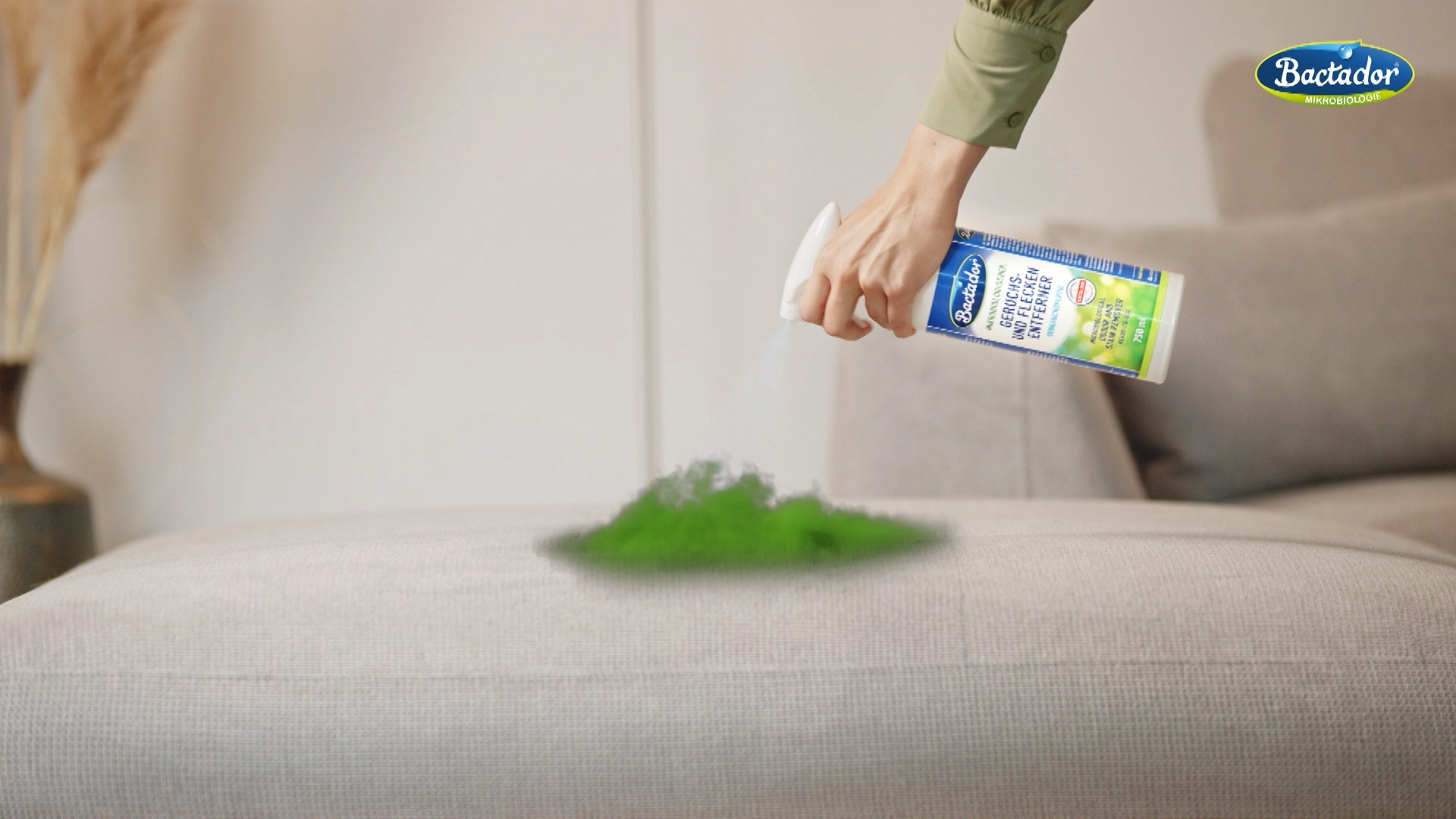 Hand sprüht Bactador Fleckenentferner auf einen digital dargestellten grünen Fleck auf einem Sofa. Dieses Produkt-Detailbild stammt aus einer Spot-Produktion der Panda Pictures Filmproduktion München Ulm Videoproduktion.