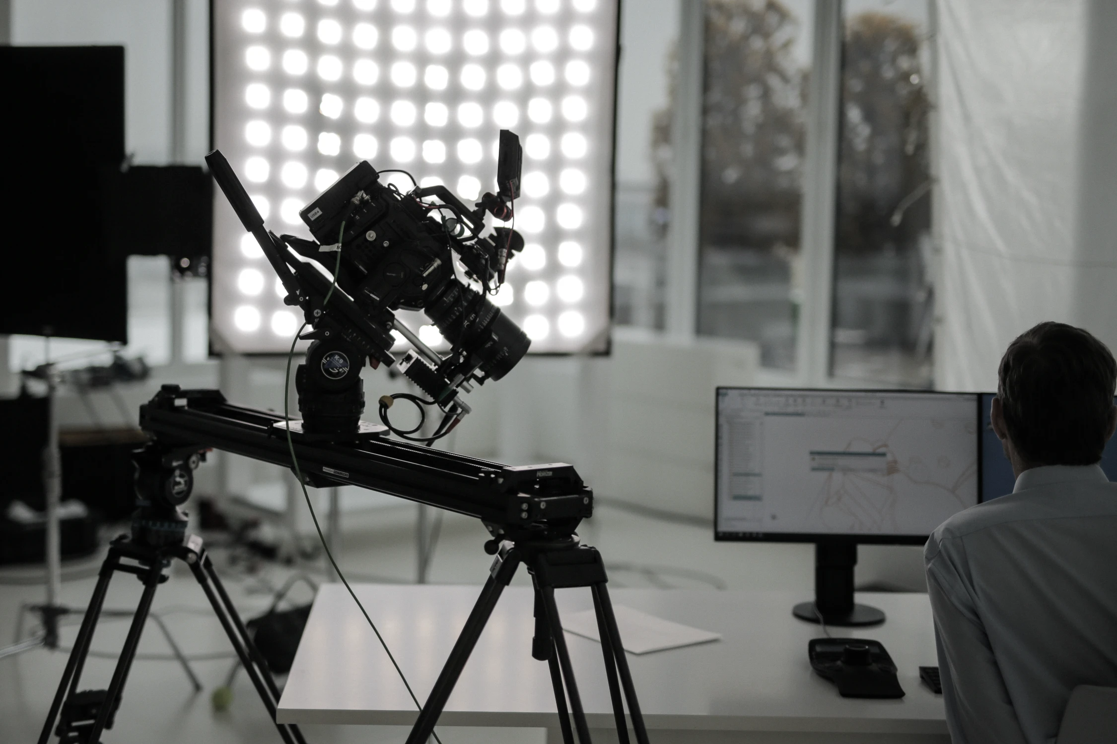 Ein Filmset mit Kamera auf Stativ, LED-Lichtpanel und einer Person am Monitor. Eine typische Szene für die Panda Pictures München Ulm Filmproduktion.