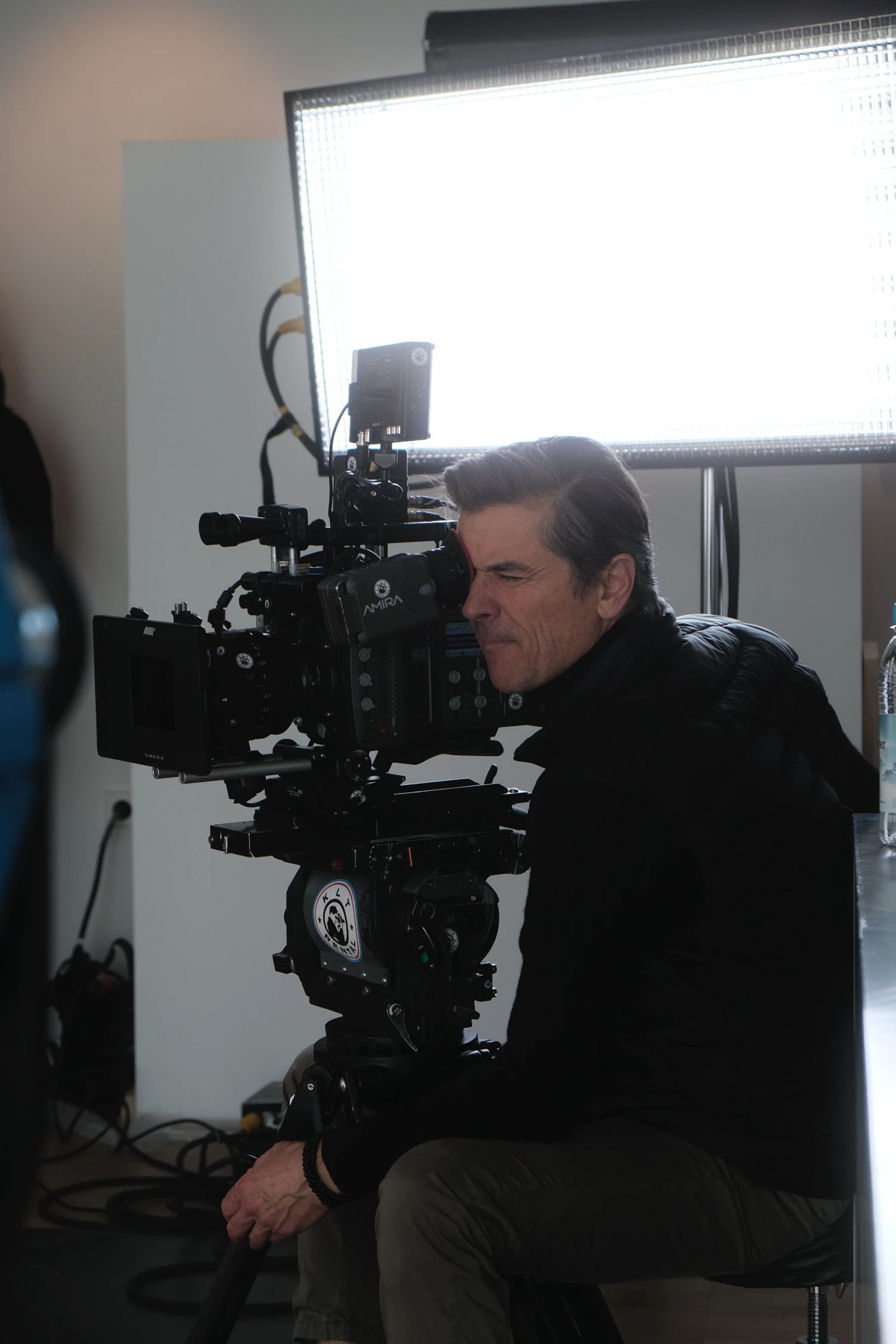 Eine konzentrierte Kamerakraft an einer professionellen ARRI Amira Filmkamera mit LED-Licht im Hintergrund. Eine engagierte Aufnahme der Panda Pictures München Ulm Filmproduktion.