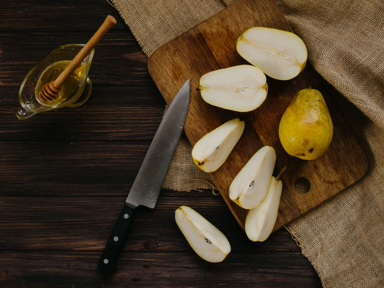 Pear slices and a knife on a cutting board, ready to serve to a dog