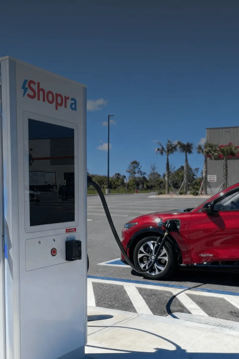 Base Station EV charging station positioned outside a big-box retail store, offering a convenient amenity for shoppers. The sleek design of the charging station stands prominently, with bollards securing the area in the foreground and the store visible