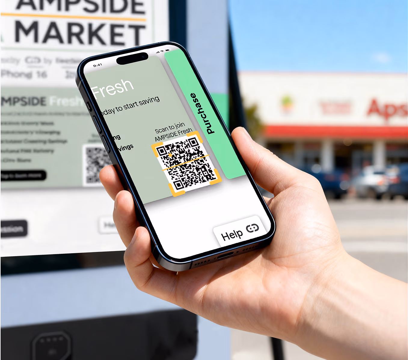 A person holding a smartphone displaying the AMPSIDE Fresh membership QR code for easy sign-up. The background shows the AMPSIDE Market storefront, with a clear view of the EV charging station and cars in the parking lot.