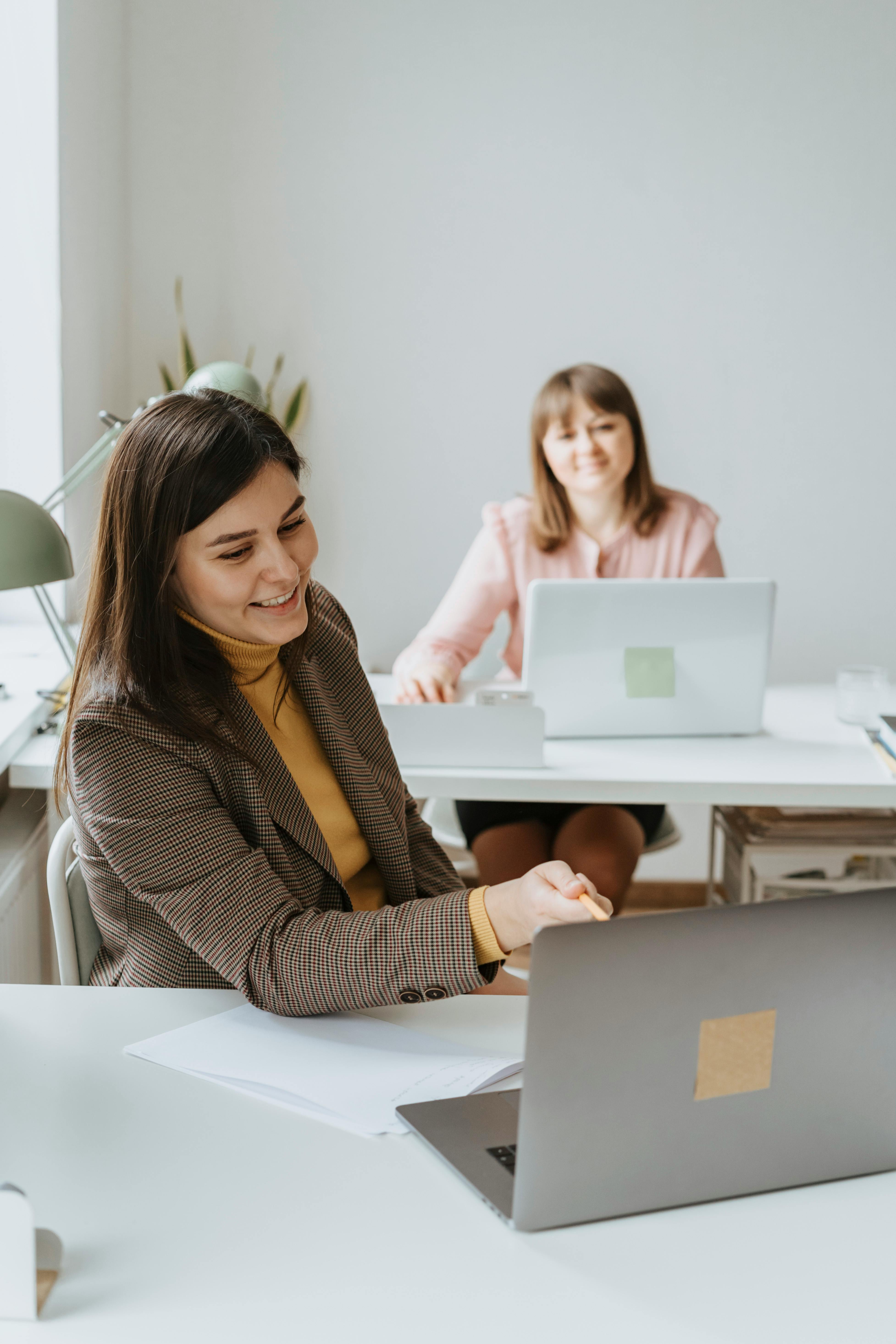 Two professionals working at laptops in an office