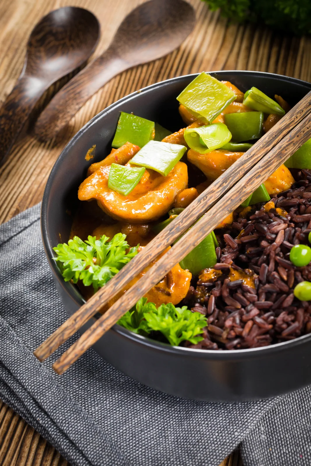 A bowl of rice, vegetables and curry with chopsticks