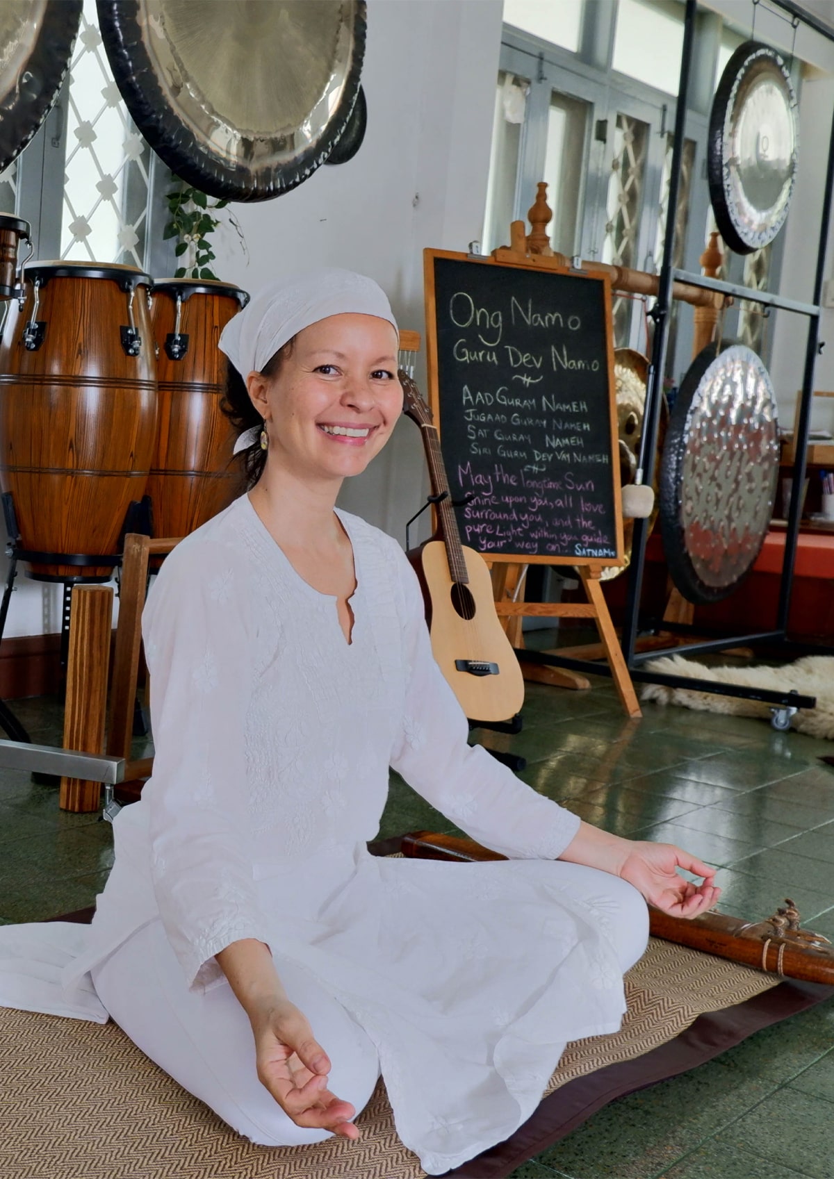 Melanie Irene Giles seated beside gongs at Lotus Wellness