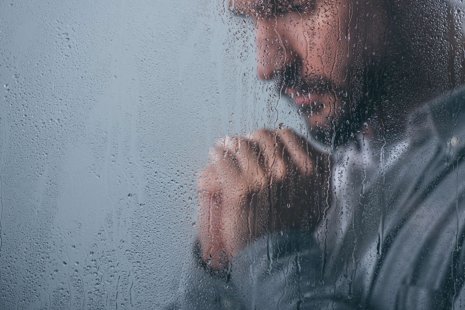 Man seen through a rain-covered window