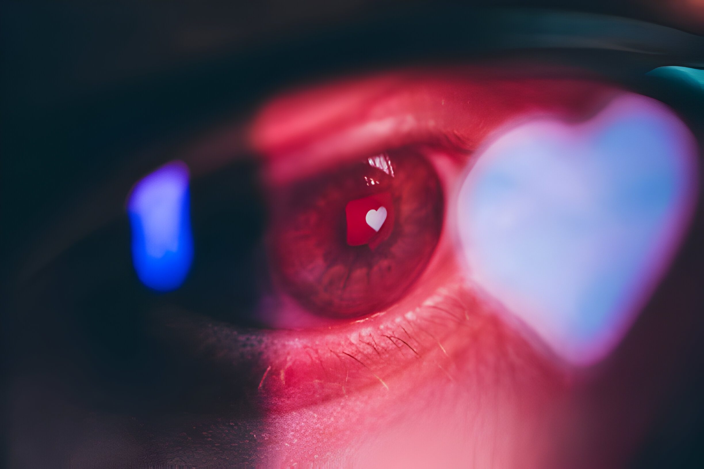 Close-up of an eye behind glasses reflecting a heart