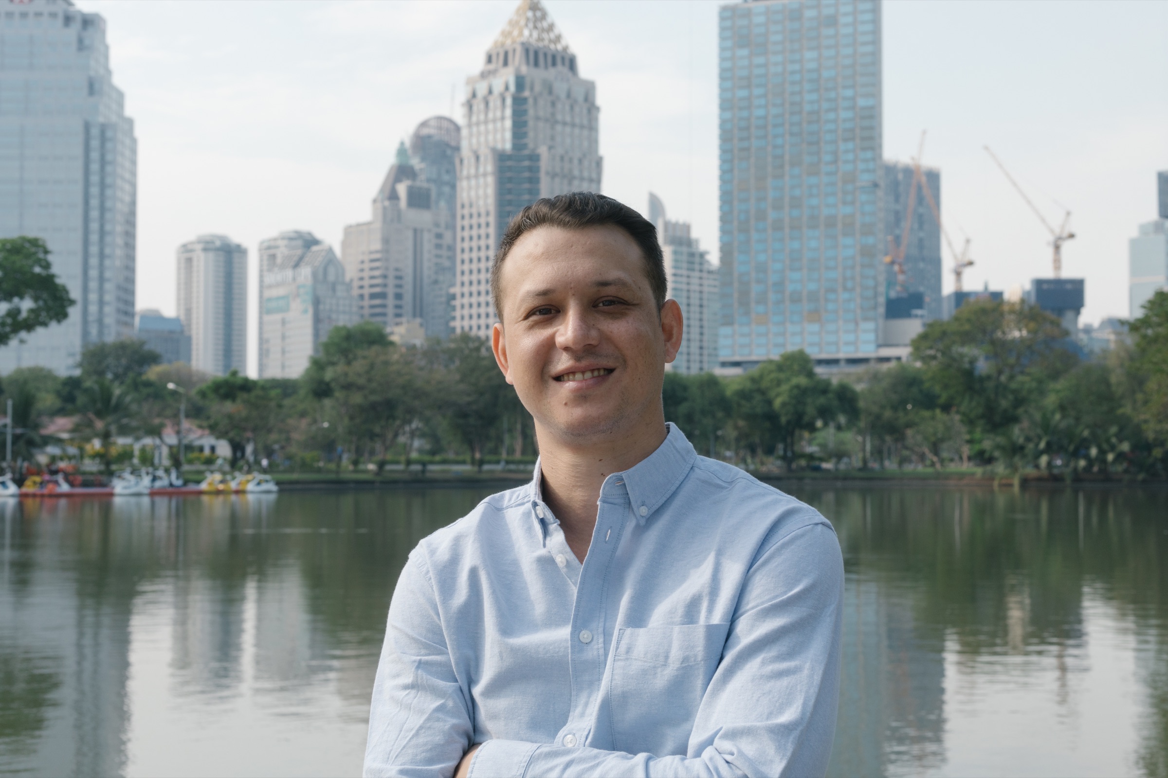 Benjamin Barshai beside a lake with the Bangkok skyline behind him
