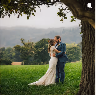 A bride and groom under an oak tree after their wedding in Conwy Valley, North Wales 
