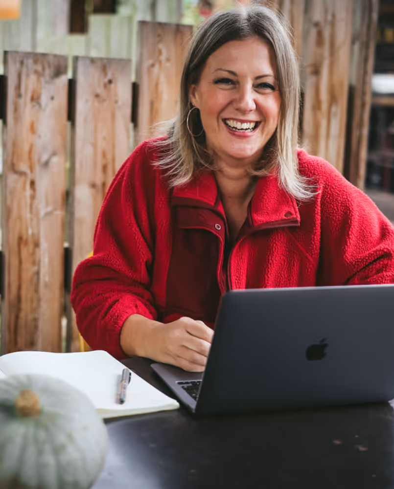 Kate smiling at the camera whilst working on a laptop