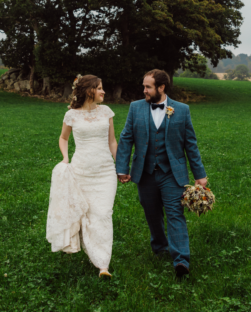 Bride Chloe and groom Rich walking hand in hand through a green field after their celebrant-led wedding ceremony, with relaxed countryside vibes and natural photography.