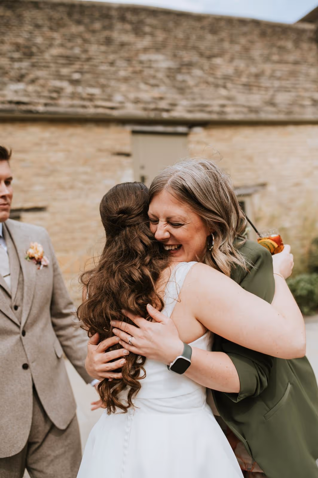 Wedding celebrant Kate Rostance hugging bride Hayley after her ceremony at Caswell House, with groom Adam looking on.
