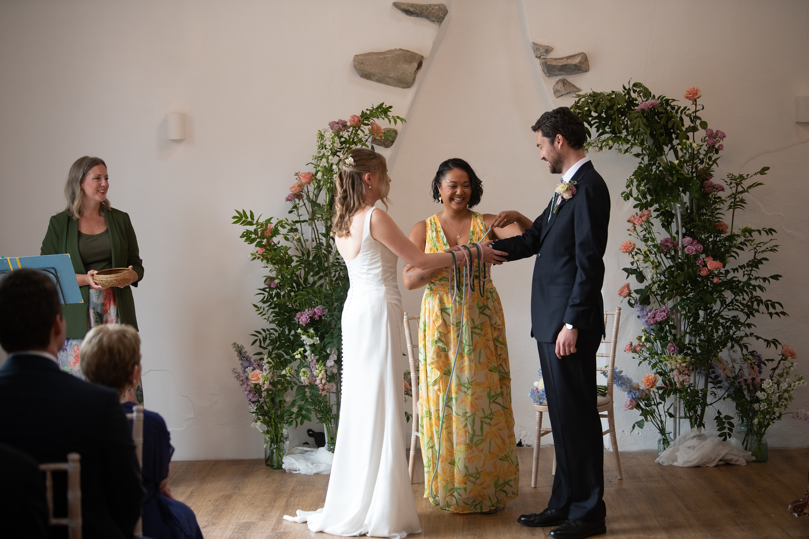 Emily and David take part in a colourful handfasting ritual led by celebrant Kate Rostance during their Talhenbont Hall wedding ceremony in North Wales.
